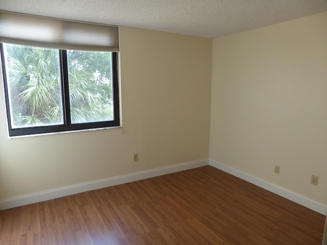 unfurnished room with a textured ceiling and dark wood-type flooring