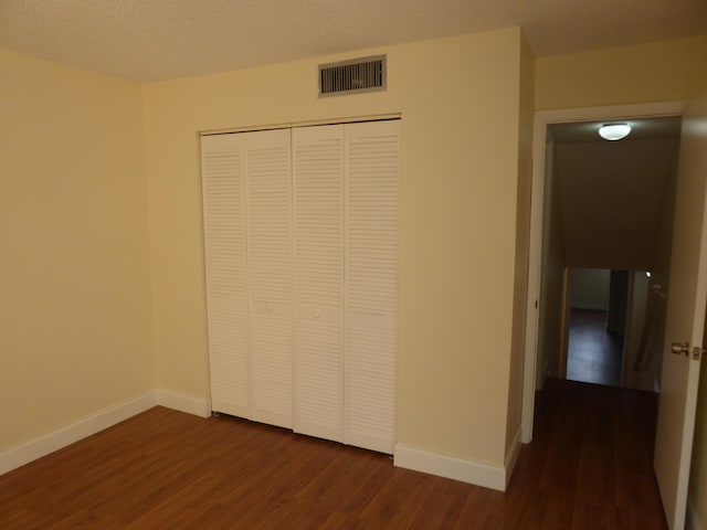 unfurnished bedroom featuring dark hardwood / wood-style flooring, a closet, and a textured ceiling