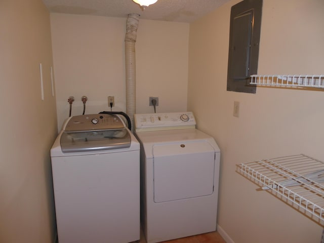 washroom with a textured ceiling, washing machine and dryer, and electric panel