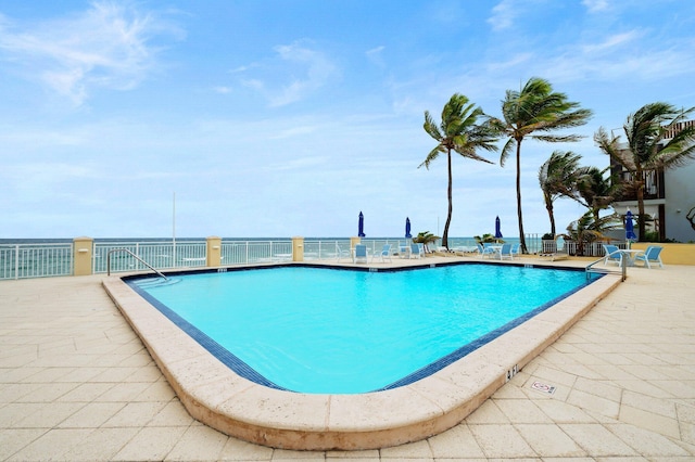 view of swimming pool with a patio area and a water view