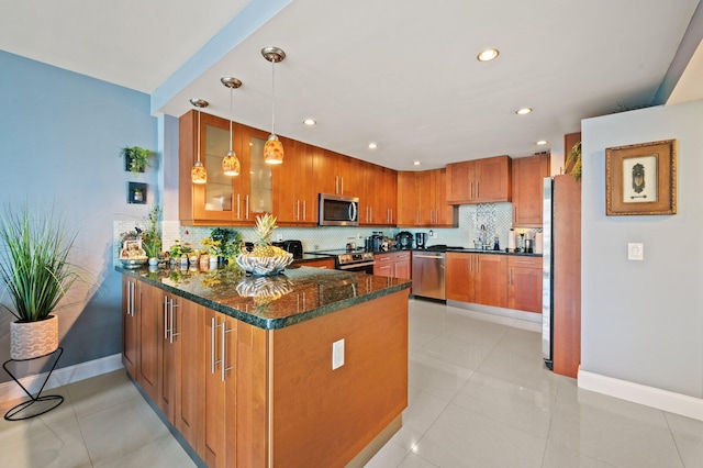 kitchen featuring pendant lighting, dark stone counters, light tile patterned floors, appliances with stainless steel finishes, and kitchen peninsula