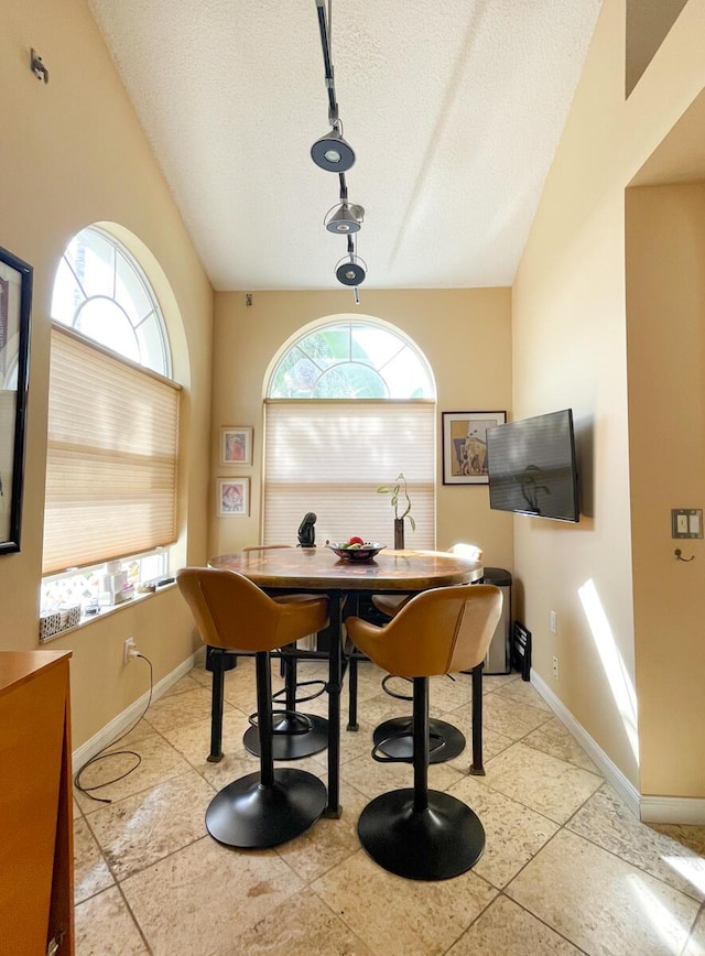 misc room with lofted ceiling, light tile patterned flooring, and a textured ceiling