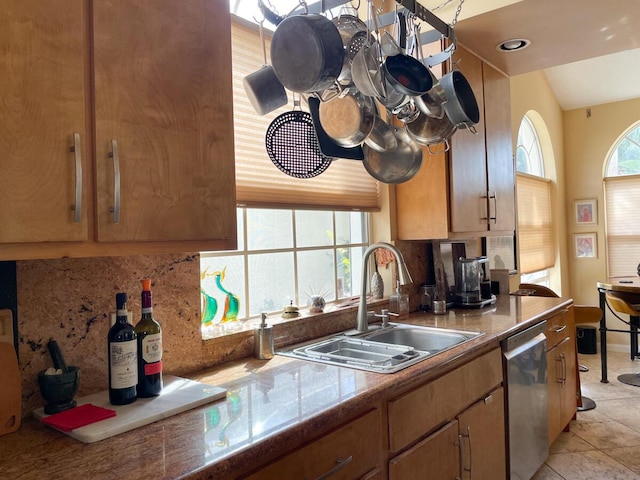 kitchen featuring dishwasher, sink, backsplash, lofted ceiling, and light tile patterned flooring