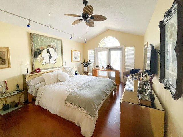 bedroom with a textured ceiling, ceiling fan, dark wood-type flooring, and vaulted ceiling