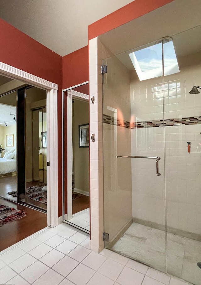 bathroom featuring a skylight, tile patterned flooring, and a shower with door