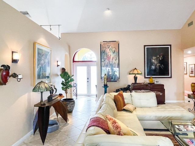 tiled living room featuring french doors, track lighting, and vaulted ceiling