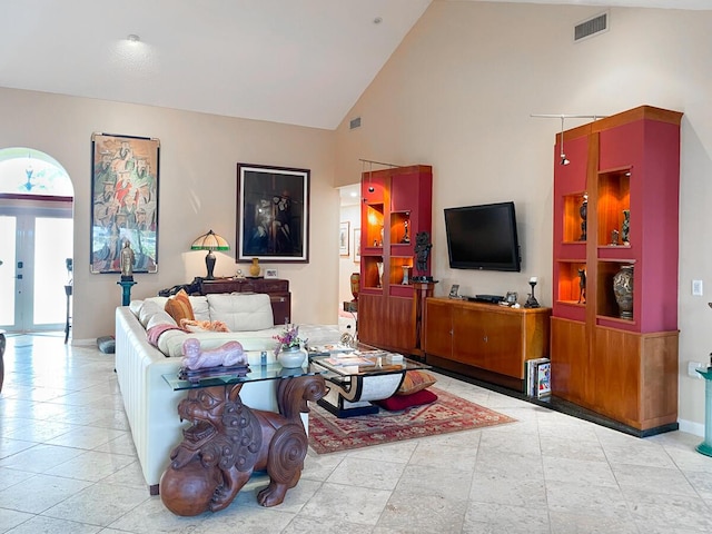 tiled living room with plenty of natural light, high vaulted ceiling, and french doors