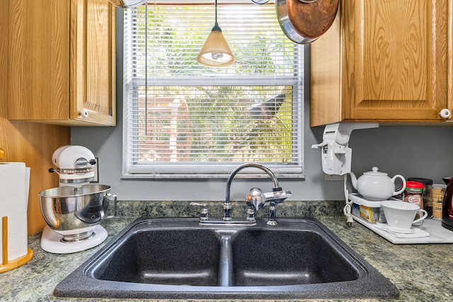 kitchen with decorative light fixtures, sink, and dark stone counters