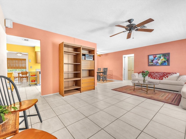 living room featuring a textured ceiling, ceiling fan, and light tile floors