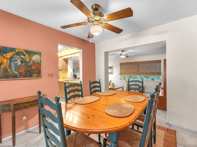 tiled dining room with sink, ceiling fan, and a textured ceiling