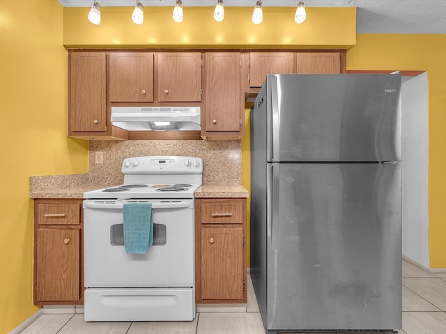 kitchen featuring electric range, stainless steel fridge, light tile floors, and backsplash