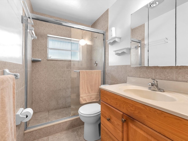 bathroom featuring tile floors, tile walls, a shower with door, vanity, and toilet