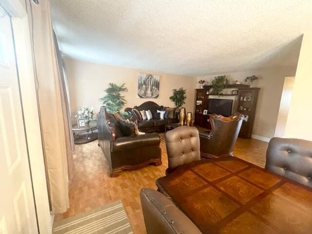 living room featuring a textured ceiling, baseboards, and wood finished floors