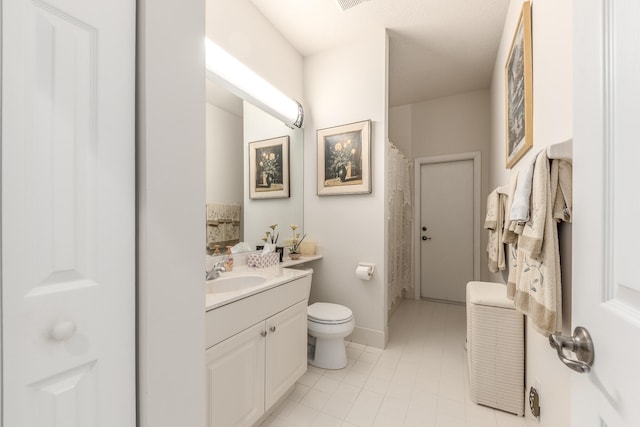 bathroom with toilet, vanity, and tile patterned floors