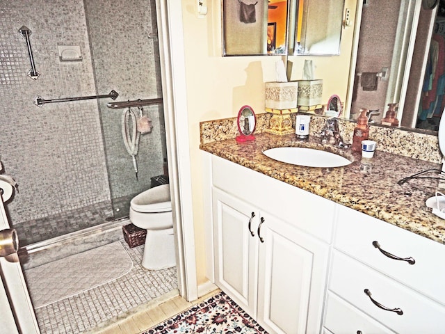 bathroom with tile patterned floors, a shower with door, vanity, and toilet