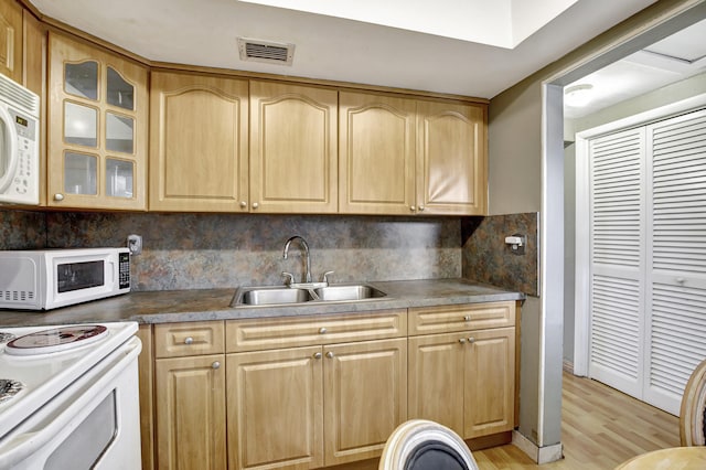 kitchen featuring light brown cabinetry, light hardwood / wood-style flooring, backsplash, sink, and white appliances