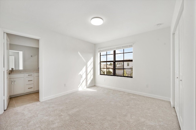 unfurnished bedroom with ensuite bath and light colored carpet