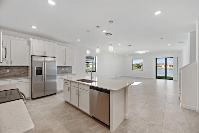 kitchen with white cabinets, a center island with sink, sink, a wealth of natural light, and stainless steel appliances