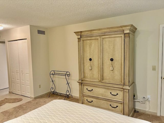 bedroom with a textured ceiling, light carpet, and a closet