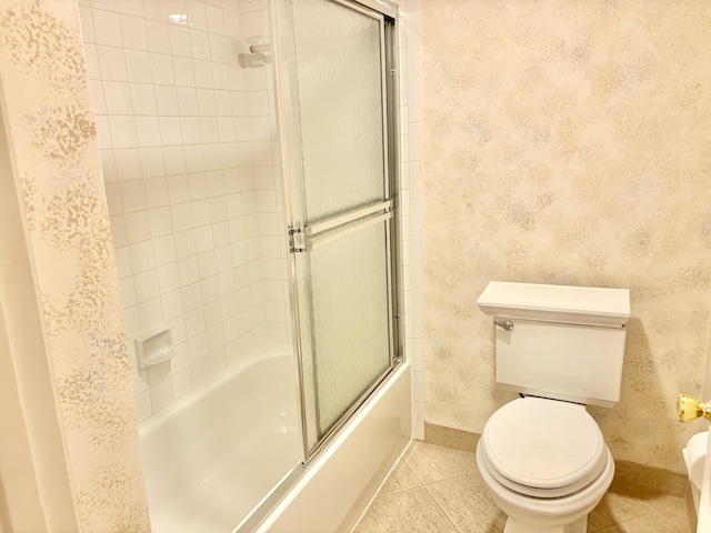 bathroom with tile patterned floors, toilet, and shower / bath combination with glass door