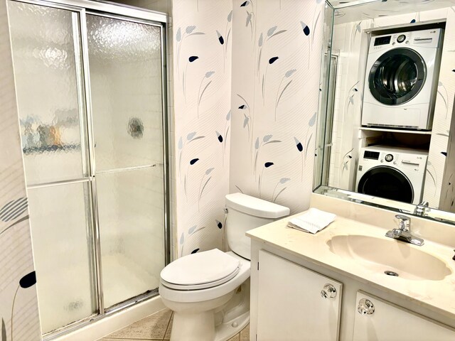 bathroom with a shower with shower door, tile patterned flooring, toilet, stacked washer / dryer, and vanity