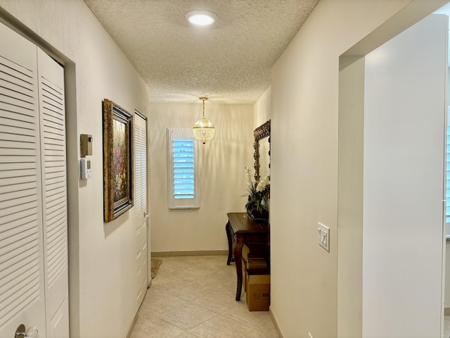 hall featuring light tile patterned flooring and a textured ceiling