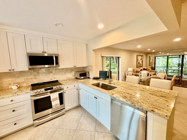 kitchen featuring kitchen peninsula, white cabinetry, stainless steel appliances, and light stone counters