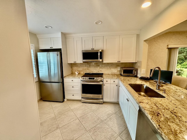 kitchen with decorative backsplash, sink, stainless steel appliances, and white cabinets