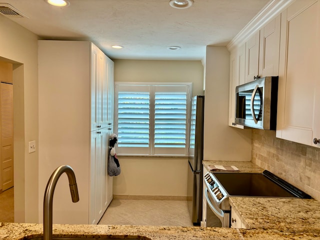 kitchen with light stone countertops, white cabinetry, appliances with stainless steel finishes, and tasteful backsplash