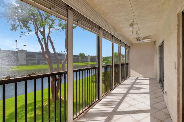 unfurnished sunroom with ceiling fan and a water view