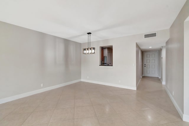 tiled spare room with a chandelier