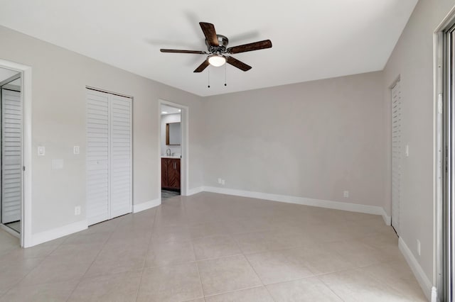 unfurnished bedroom with ceiling fan, ensuite bathroom, and light tile patterned flooring