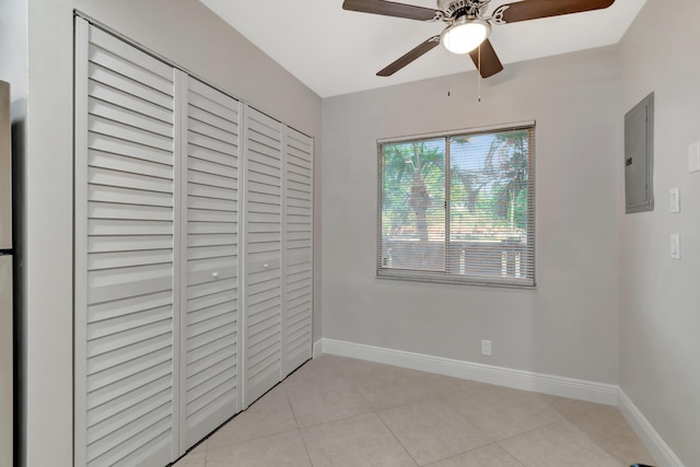 unfurnished bedroom with light tile patterned flooring, ceiling fan, electric panel, and a closet