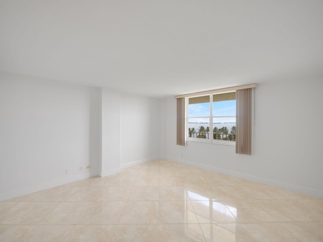 spare room featuring light tile patterned floors and baseboards