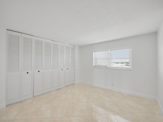 unfurnished bedroom featuring baseboards and a textured ceiling