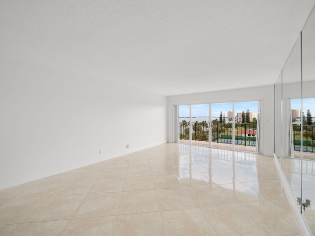 spare room featuring light tile patterned floors, a textured ceiling, and baseboards