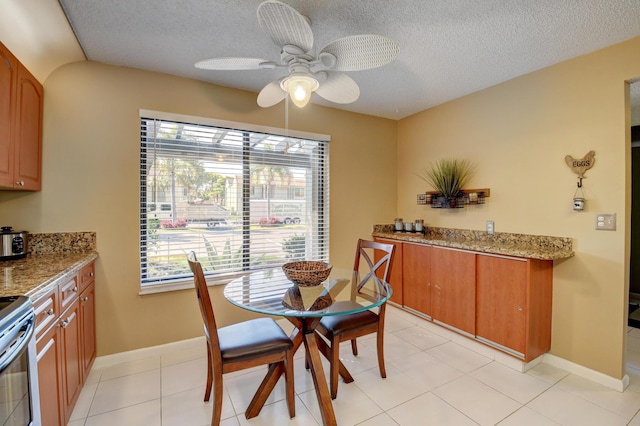 dining area with ceiling fan, light tile patterned floors, and a textured ceiling