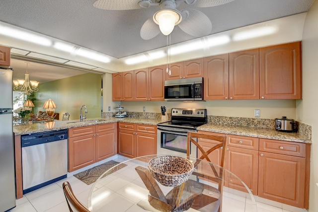 kitchen with light stone counters, sink, a textured ceiling, and appliances with stainless steel finishes