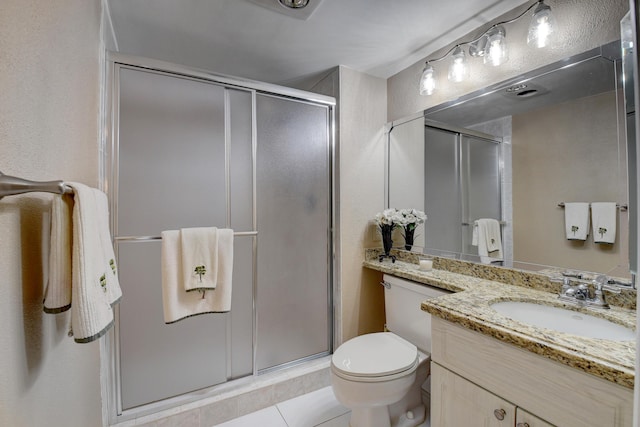 bathroom featuring tile patterned flooring, vanity, toilet, and a shower with door