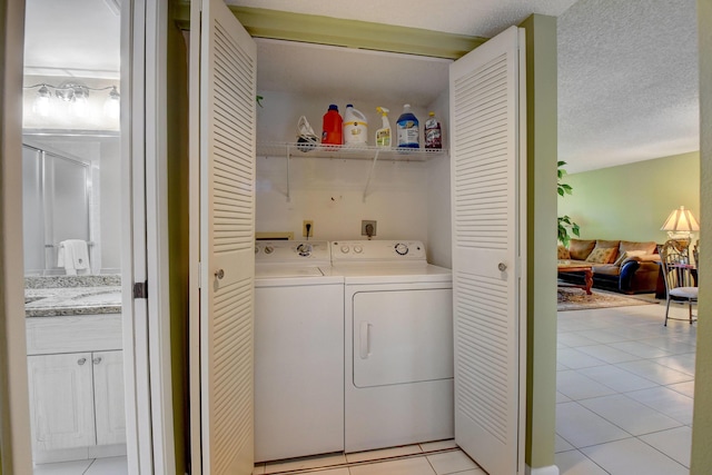 laundry area featuring washer and clothes dryer, light tile patterned floors, and a textured ceiling