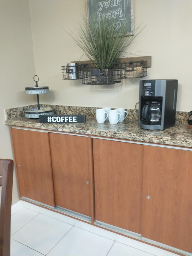 bar with light tile patterned floors and stone countertops