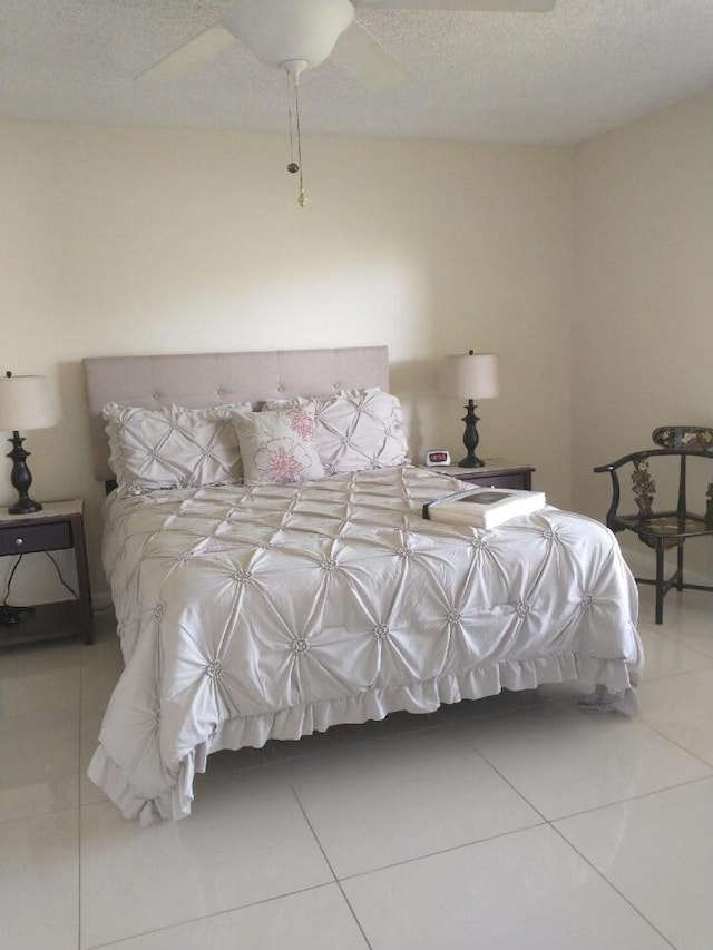 tiled bedroom featuring ceiling fan and a textured ceiling