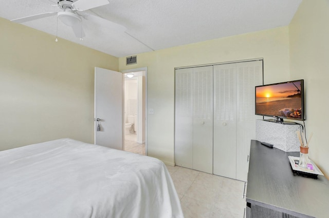 bedroom featuring a textured ceiling, a closet, ceiling fan, and light tile floors