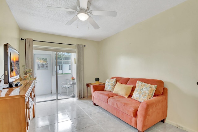 living room featuring ceiling fan, a textured ceiling, and light tile floors