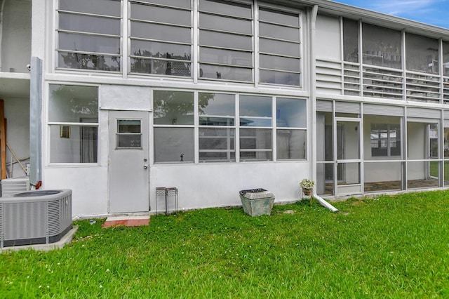 rear view of property featuring central AC and a lawn