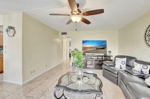 living room featuring a textured ceiling, ceiling fan, and light tile floors