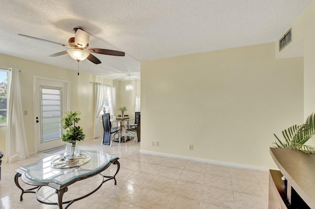 interior space featuring ceiling fan, a textured ceiling, a wealth of natural light, and light tile floors