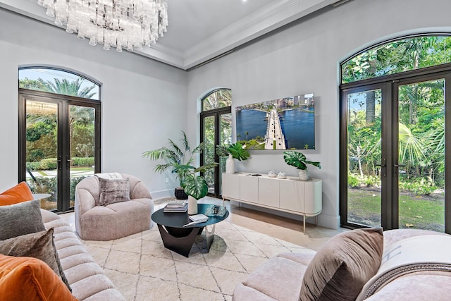 living room featuring ornamental molding, french doors, light wood-type flooring, and a chandelier