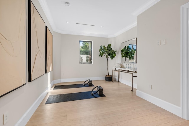 workout room with light hardwood / wood-style floors and crown molding