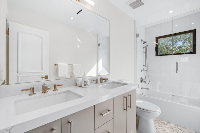 full bathroom featuring vanity, bath / shower combo with glass door, and toilet